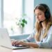 Assistante virtuelle avec casque travaillant sur un ordinateur portable dans un bureau lumineux