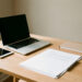 Bureau moderne de petite entreprise avec ordinateur portable, tablette, documents vierges et agenda, éclairé par la lumière naturelle.