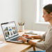 Une femme freelance organise des photos professionnelles sur un ordinateur portable dans un bureau lumineux, sobre et bien rangé.